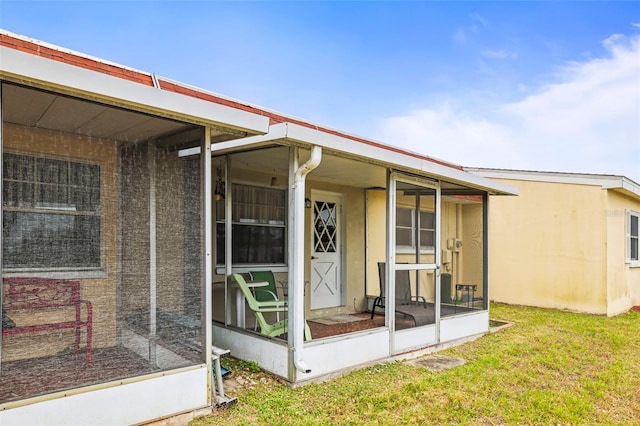 back of property with a sunroom and a yard