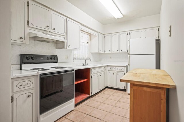 kitchen featuring electric range, under cabinet range hood, a sink, freestanding refrigerator, and light tile patterned floors