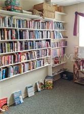 sitting room featuring wall of books and carpet flooring