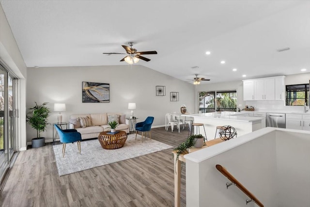 living room with lofted ceiling, light wood finished floors, a ceiling fan, baseboards, and recessed lighting