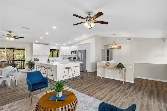 living room with a ceiling fan, lofted ceiling, recessed lighting, light wood-type flooring, and baseboards
