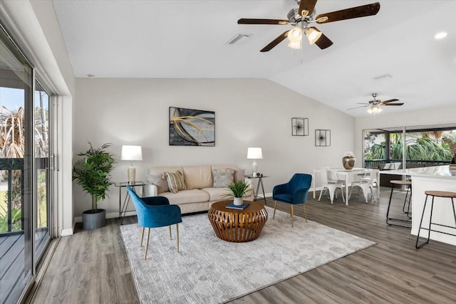 living area featuring a ceiling fan, healthy amount of natural light, vaulted ceiling, and wood finished floors