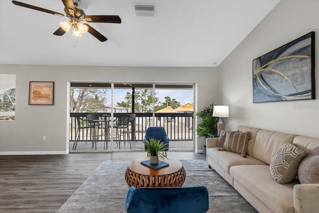 living area featuring baseboards, ceiling fan, wood finished floors, and vaulted ceiling