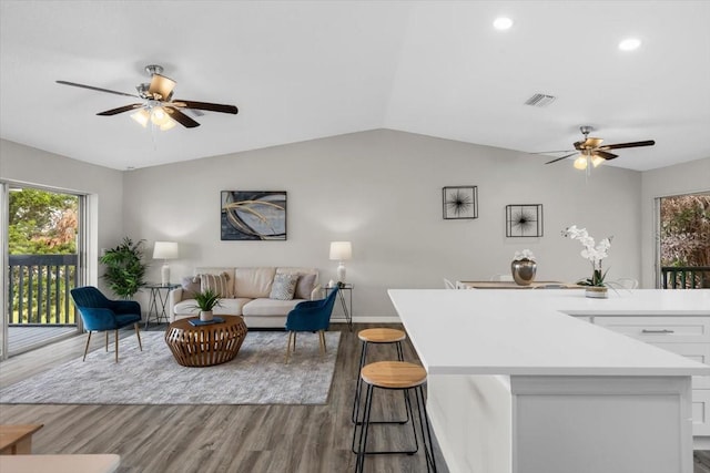 living area featuring ceiling fan, wood finished floors, lofted ceiling, baseboards, and recessed lighting