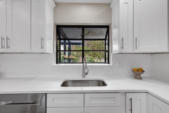 kitchen featuring dishwasher, a sink, and white cabinets
