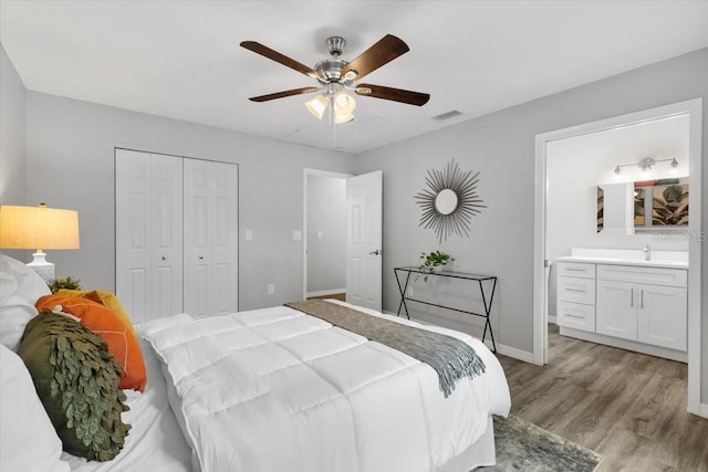 bedroom featuring light wood-style floors, a sink, a closet, baseboards, and ensuite bathroom