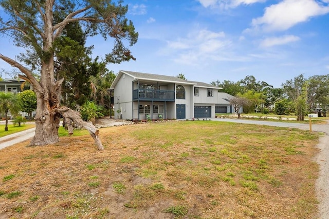 back of house with an attached garage, driveway, a yard, and a balcony
