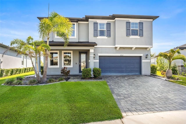 34307 Radley Way, Wesley Chapel, FL 33545 - view of front of home featuring an attached garage, decorative driveway, a front yard, stucco siding, and a porch