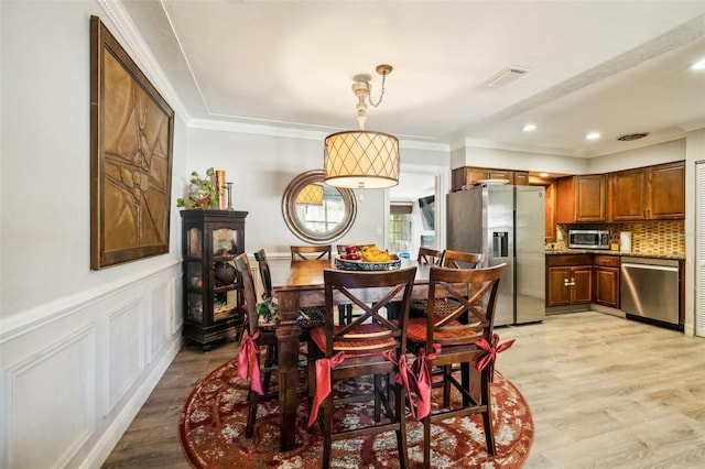 5245 18th St N, Saint Petersburg, FL 33714 - dining area featuring light wood-style floors, ornamental molding, a wainscoted wall, and recessed lighting