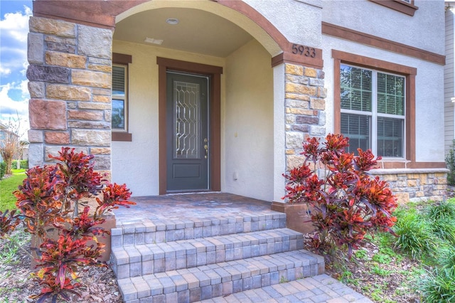property entrance with stone siding and stucco siding