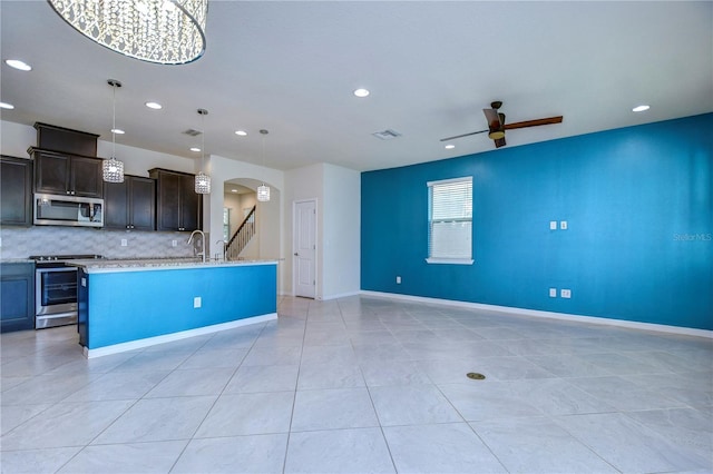 kitchen featuring appliances with stainless steel finishes, arched walkways, open floor plan, a ceiling fan, and recessed lighting