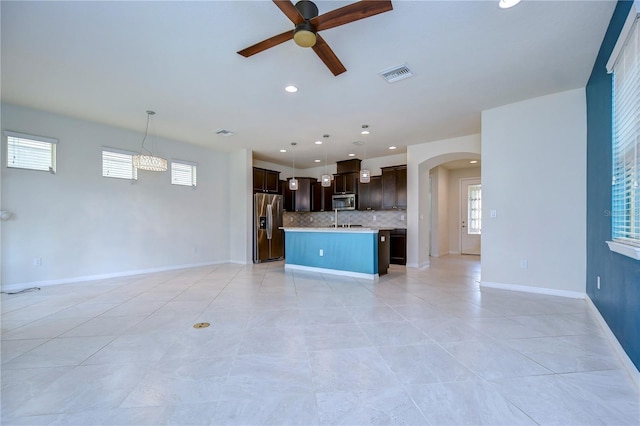 unfurnished living room featuring a ceiling fan, arched walkways, recessed lighting, healthy amount of natural light, and baseboards