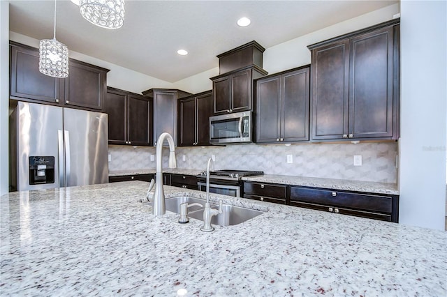 kitchen with stainless steel appliances, dark brown cabinets, light stone counters, decorative light fixtures, and recessed lighting