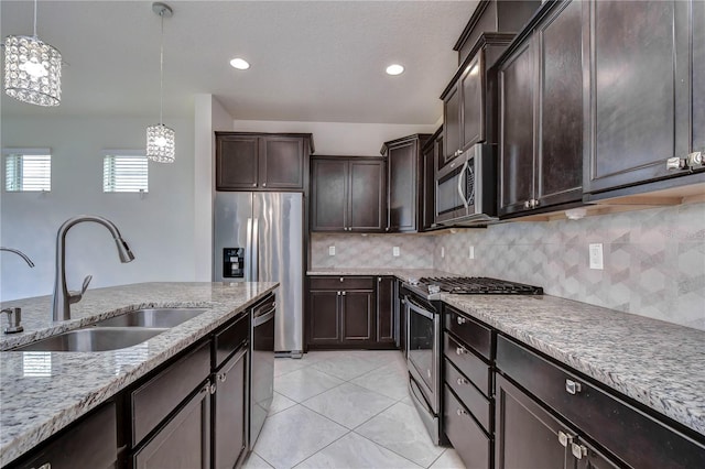 kitchen with stainless steel appliances, a sink, decorative light fixtures, dark brown cabinets, and light stone counters