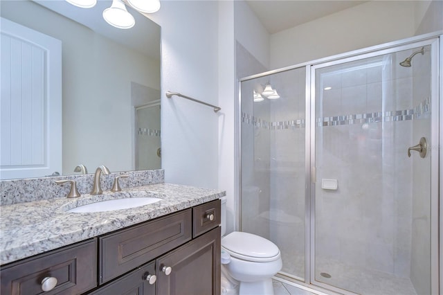 bathroom with a stall shower, toilet, and vanity
