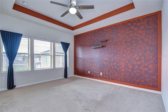 spare room with carpet, a raised ceiling, baseboards, ceiling fan, and a smoke detector