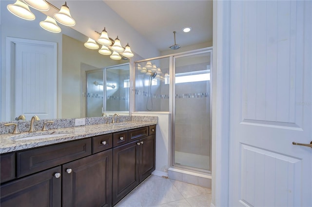 bathroom with a shower stall, double vanity, and tile patterned floors
