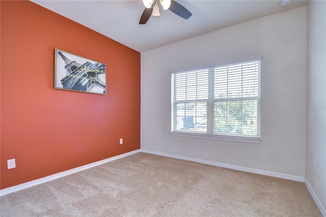 carpeted empty room with ceiling fan and baseboards