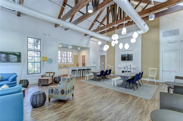 living area featuring high vaulted ceiling, light wood-style floors, beam ceiling, and baseboards