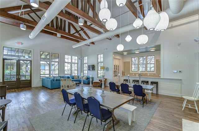 dining room featuring high vaulted ceiling, beamed ceiling, wood finished floors, and baseboards