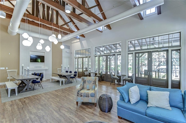 living room featuring a towering ceiling, wood finished floors, and french doors