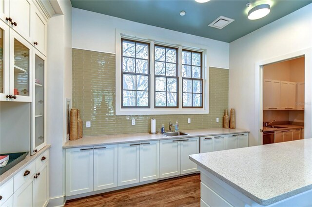 kitchen with a sink, white cabinetry, dark wood-type flooring, and light countertops