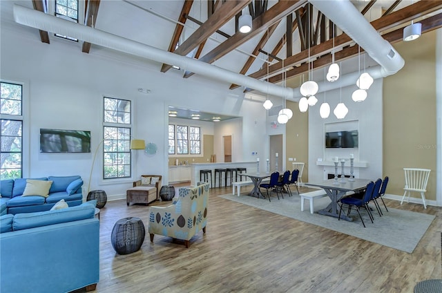 living room with high vaulted ceiling, wood finished floors, and baseboards