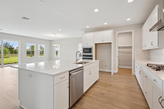 kitchen featuring stainless steel appliances, a sink, tasteful backsplash, white cabinets, and light countertops