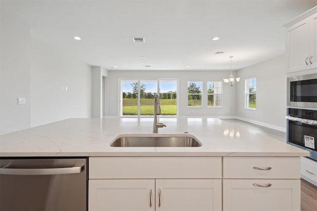 kitchen featuring appliances with stainless steel finishes, a sink, plenty of natural light, light stone countertops, and recessed lighting