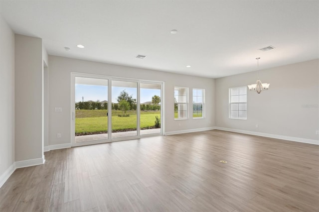 unfurnished living room with a chandelier, baseboards, recessed lighting, and wood finished floors