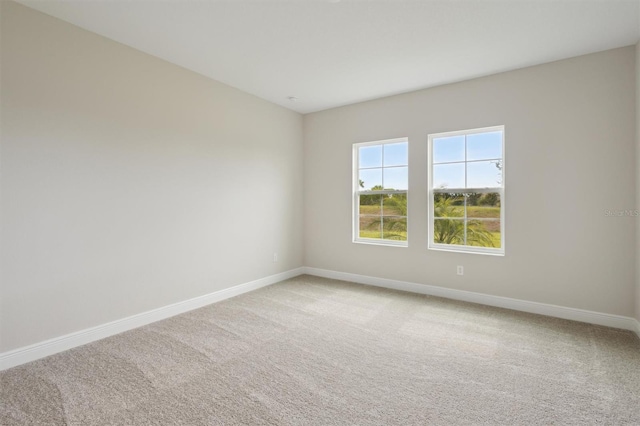 unfurnished room with baseboards and light carpet