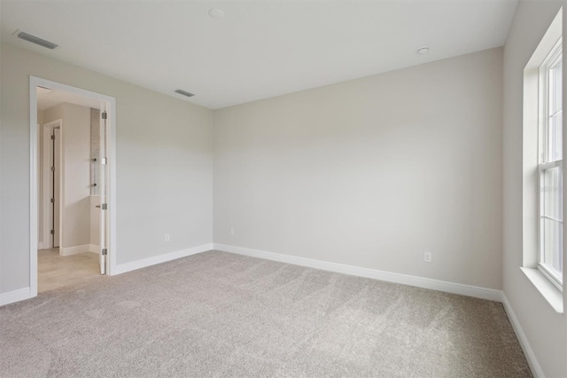 unfurnished room featuring light colored carpet and baseboards