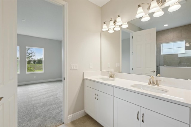 bathroom with a chandelier, baseboards, double vanity, and tiled shower