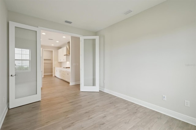 unfurnished room featuring french doors, light wood-style floors, baseboards, and recessed lighting