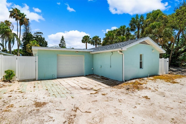 view of side of property with an attached garage, stucco siding, fence, and driveway