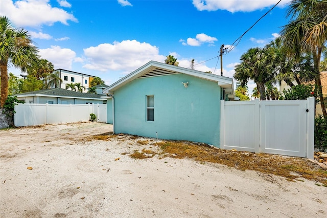 view of side of property featuring stucco siding, fence, and a gate