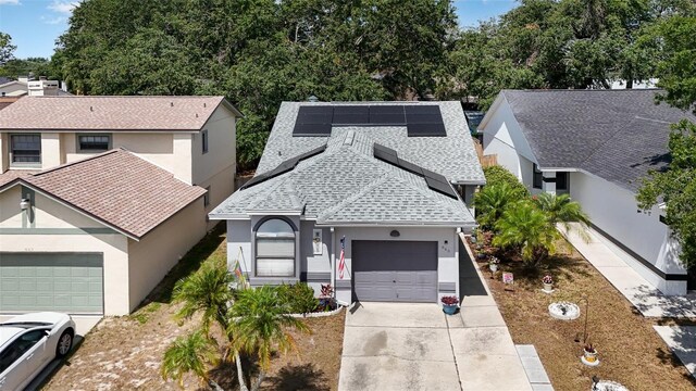 640 Lake Dexter Cir, Winter Haven, FL 33884 - view of front of house with driveway, a shingled roof, an attached garage, solar panels, and stucco siding