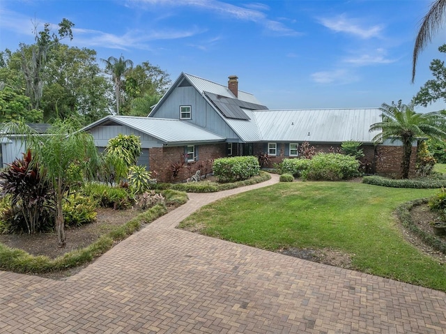 13533 Bay Lake Ln, Tampa, FL 33618 - view of front of home featuring brick siding, metal roof, a front yard, a chimney, and solar panels