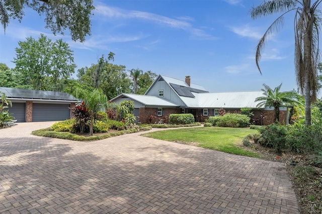 13533 Bay Lake Ln, Tampa, FL 33618 - single story home with solar panels, a chimney, a front lawn, decorative driveway, and metal roof