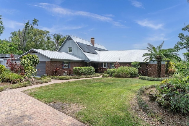 13533 Bay Lake Ln, Tampa, FL 33618 - view of front of house featuring metal roof, a front yard, brick siding, and a chimney