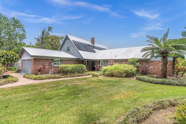 13533 Bay Lake Ln, Tampa, FL 33618 - view of front of property with brick siding, metal roof, a chimney, a front yard, and a garage