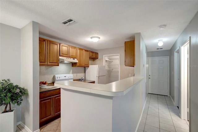 1400 Gandy Blvd N Unit 1504, Saint Petersburg, FL 33702 - kitchen with freestanding refrigerator, under cabinet range hood, light tile patterned floors, a peninsula, and light countertops
