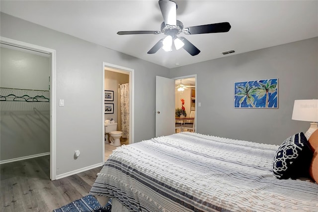 1400 Gandy Blvd N Unit 1504, Saint Petersburg, FL 33702 - bedroom featuring wood finished floors, a walk in closet, a ceiling fan, baseboards, and connected bathroom