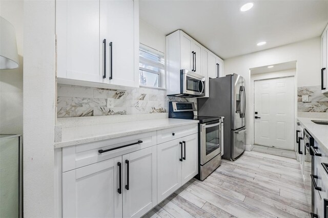 kitchen with stainless steel appliances, white cabinets, backsplash, light stone counters, and recessed lighting