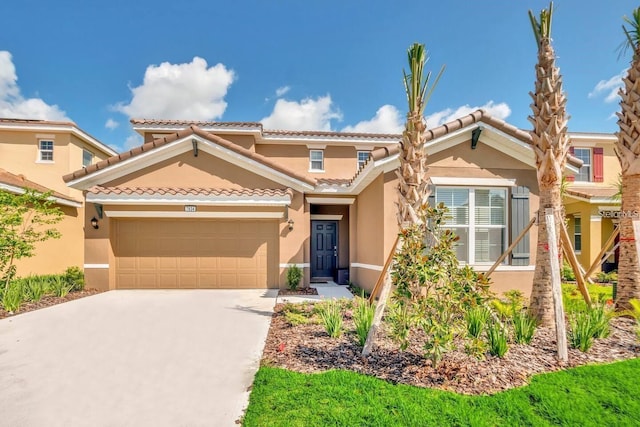 mediterranean / spanish home with stucco siding, a garage, driveway, and a tile roof
