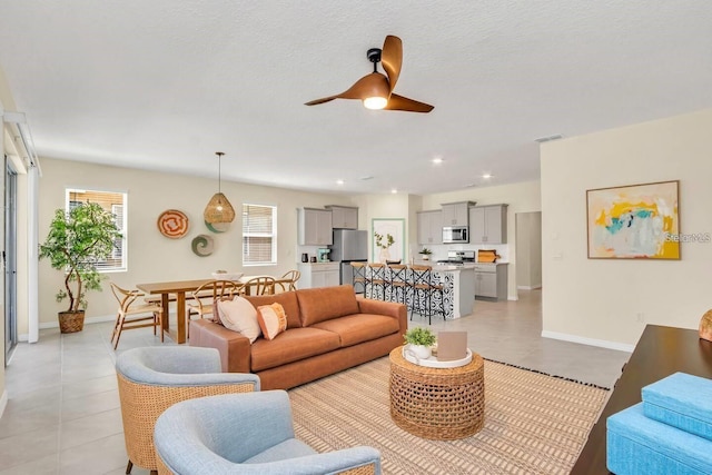 living room with a ceiling fan, light tile patterned flooring, baseboards, and recessed lighting