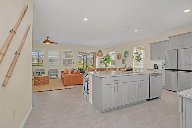 kitchen featuring appliances with stainless steel finishes, an island with sink, light tile patterned floors, a sink, and recessed lighting