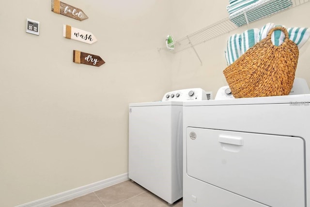 washroom with washing machine and dryer, light tile patterned flooring, and baseboards