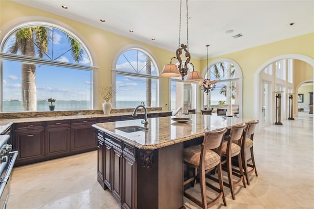 5810 Mariner St, Tampa, FL 33609 - kitchen featuring a sink, hanging light fixtures, light stone counters, a breakfast bar area, and arched walkways