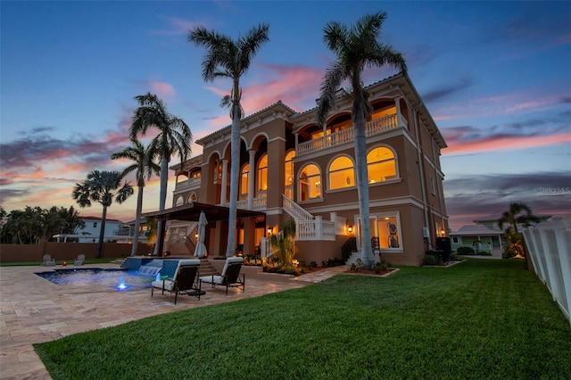 5810 Mariner St, Tampa, FL 33609 - back of house at dusk featuring a balcony, a patio, stairway, an outdoor pool, and stucco siding